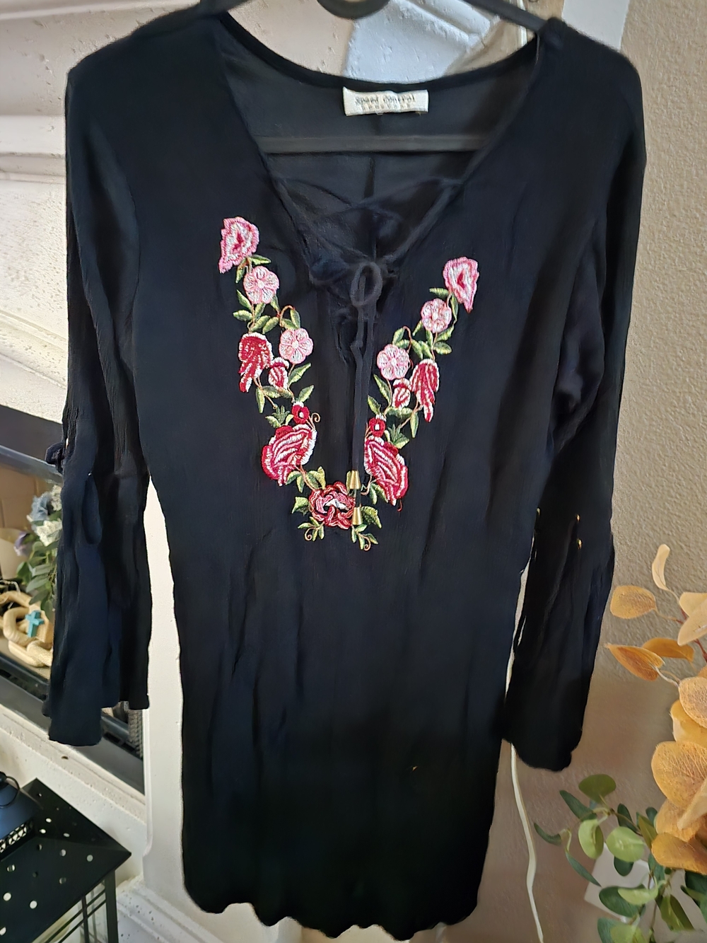 This black bohemian-style tunic dress features a laced V-neckline
